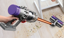 Hand holding Dyson cordless vacuum cleaning hardwood floor