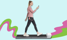 woman looking at phone while walking on treadmill with colorful background