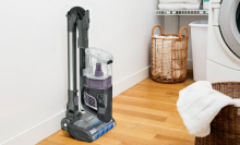 shark vertex vacuum in a laundry room with wooden floor, laundry machine behind it
