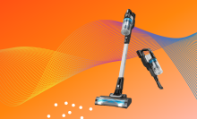 cordless stick vacuum against orange background vacuuming white dots