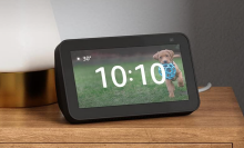 amazon echo show on a wood nightstand with a picture of a puppy on the right corner display