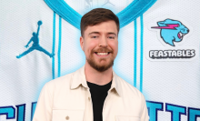 MrBeast smiling, superimposed over a photo of the top of the Hornets jersey, which features the Feastables logo on the right of the upper chest.