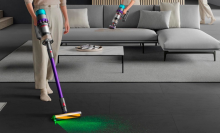 Person vacuuming the floor and couch with Dyson Gen5detect cordless vacuum