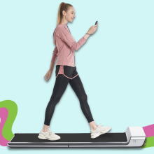 woman looking at phone while walking on treadmill with colorful background