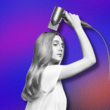 A woman holding up the Dyson Supersonic Origin to her long, flowing, light blonde locks, overlaid on a purple-orange background.