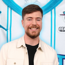 MrBeast smiling, superimposed over a photo of the top of the Hornets jersey, which features the Feastables logo on the right of the upper chest.