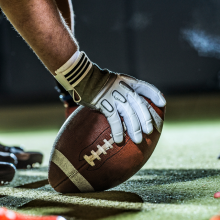 close up of football players holding ball on field