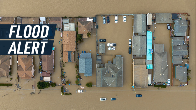 Bird's-eye view shot shows suburban houses submerged by floods. Caption reads "Flood alert."