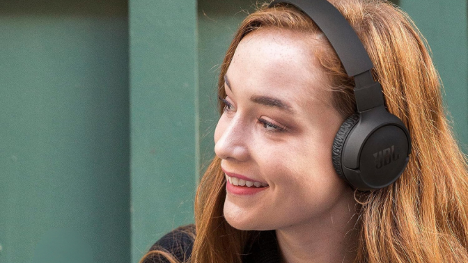 Girl with strawberry blonde hair with headphones on her head 