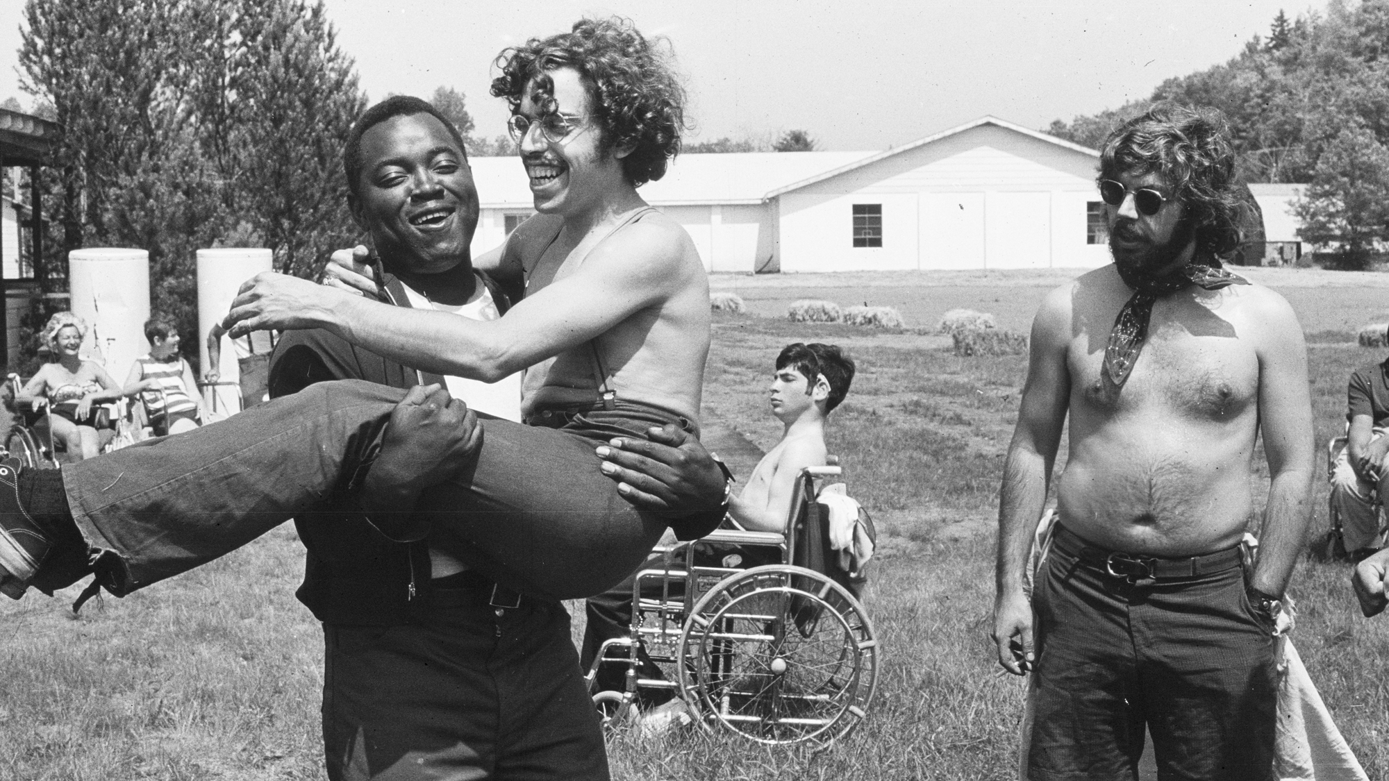 A photo from the documentary "Crip Camp" showing attendees, one carrying another in their arms.