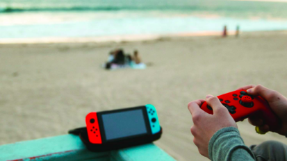 Person playing with a Nintendo Switch at the beach.
