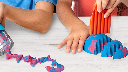 Kids playing with red and blue kinetic sand on table