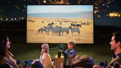 A family watching a movie about wildlife outside, using the Anker Nebula projector