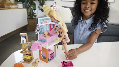 A young girl playing with her Pet Boutique Barbie playset while smiling widely